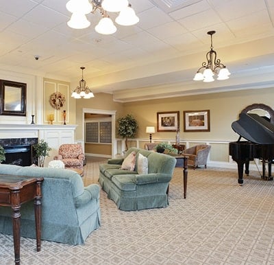 Comfortable lounge area with sofas and armchairs facing a fireplace, with a grand piano to the right in Springfield, Massachusetts.