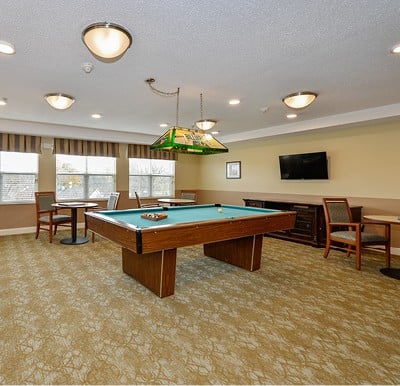 Interior room with a billiards table, large windows and ample seating.