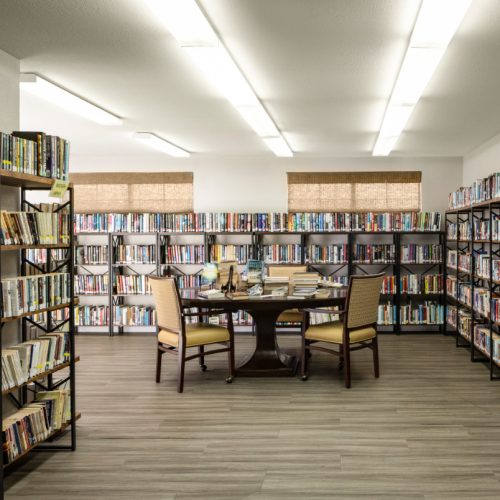 The library has multiple bookshelves with hundreds of book options for seniors to enjoy