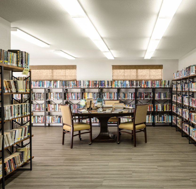 The library has multiple bookshelves with hundreds of book options for seniors to enjoy