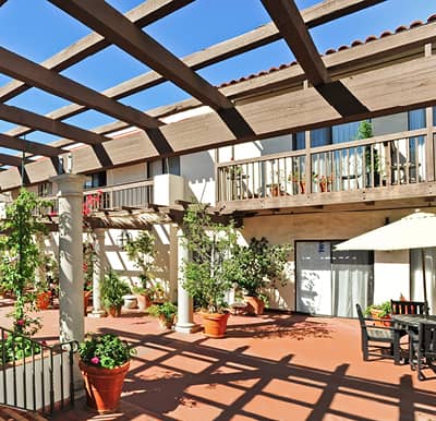 Beautiful terrace with pergola covering, outdoor seating and potted plants in Santa Barbara, California.