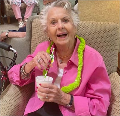 senior woman smiles while holding a drink in her hand