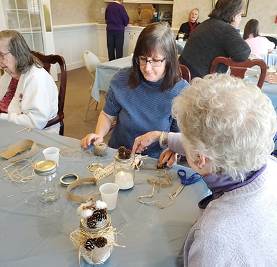 Senior woman and team member working on a craft in the activity room in Columbiana, Ohio.