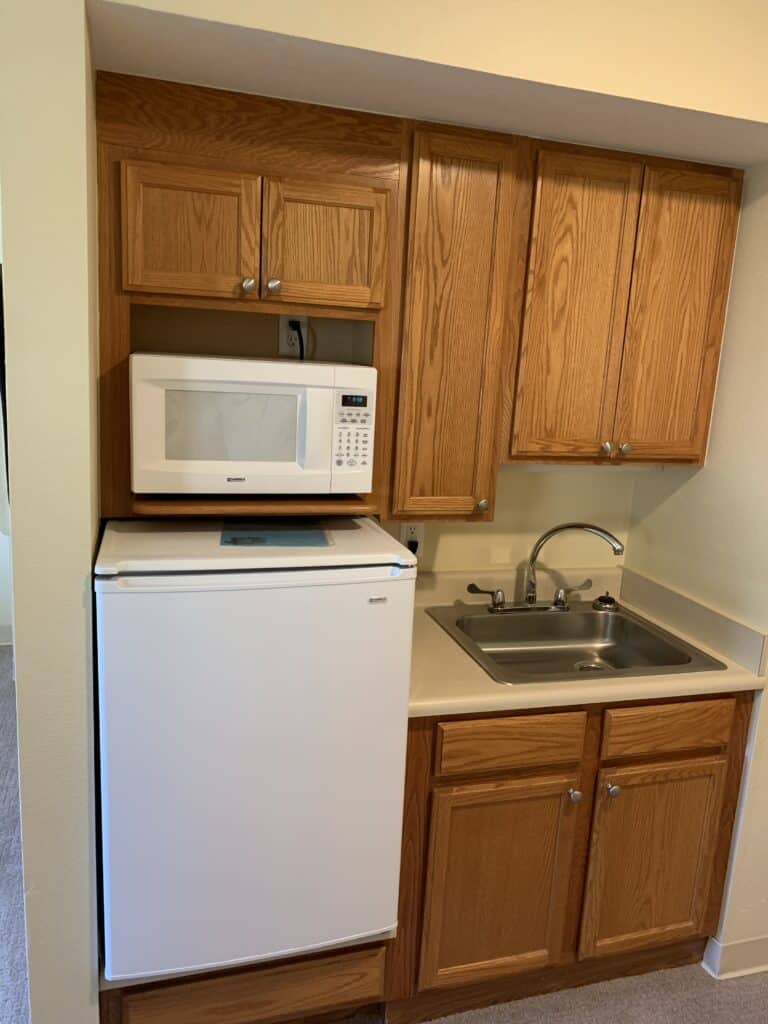 Kitchenette with microwave, small fridge and sink at senior living community in Lambertville, Michigan.