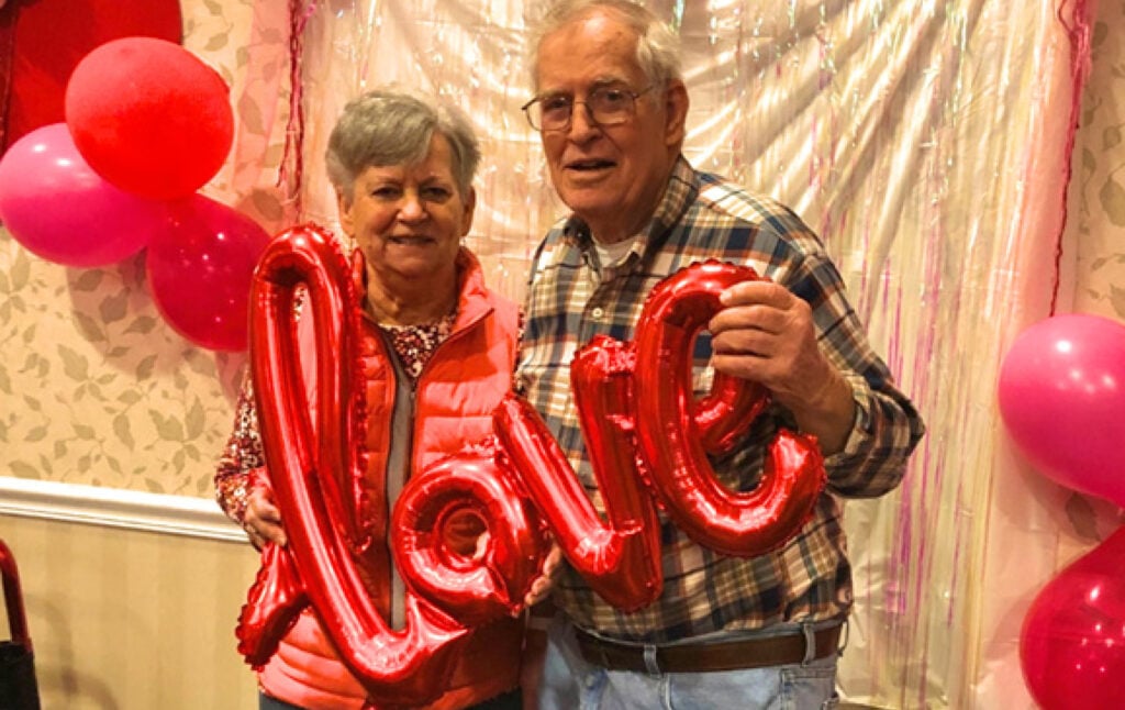Senior woman and senior man pose together at a Valentines Day event at their senior community in Greencastle, Indiana