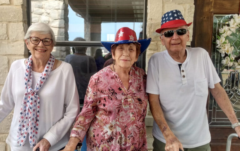 Two senior women and a senior man smile during a fourth of July party in Lake Granbury, Texas