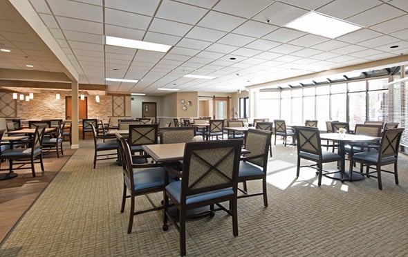 Large senior living facility dining room with many tables and large windows in Omaha, Nebraska.