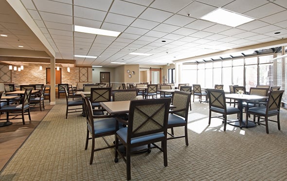 Large senior living facility dining room with many tables and large windows in Omaha, Nebraska
