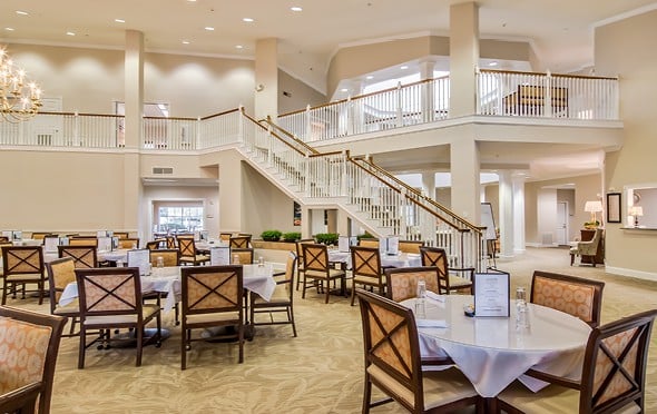 Large and elegant dining room with high ceilings and a grand staircase leading down from the upper level in San Antonio, Texas.