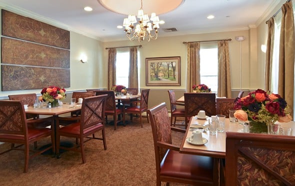 Elegant and formal dining room with a fireplace, chandeliers and many tables in Shaker Heights, Ohio.