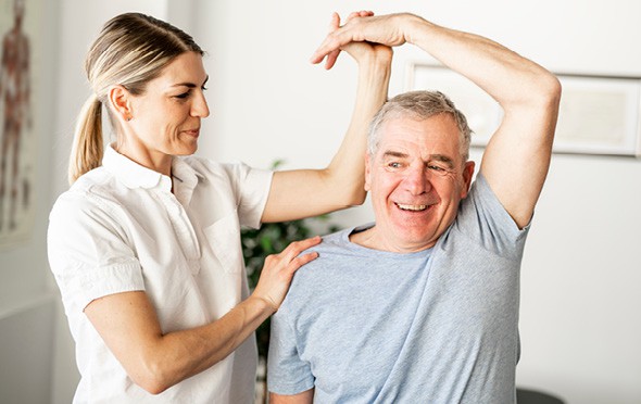 A physical therapist helping a senior stretch his tricep.