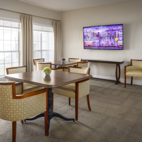 Lounge area with a flat screen TV and two tables for seniors to sit and watch a show together