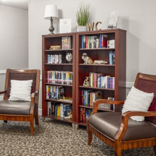 Two comfortable chairs near a large book shelf