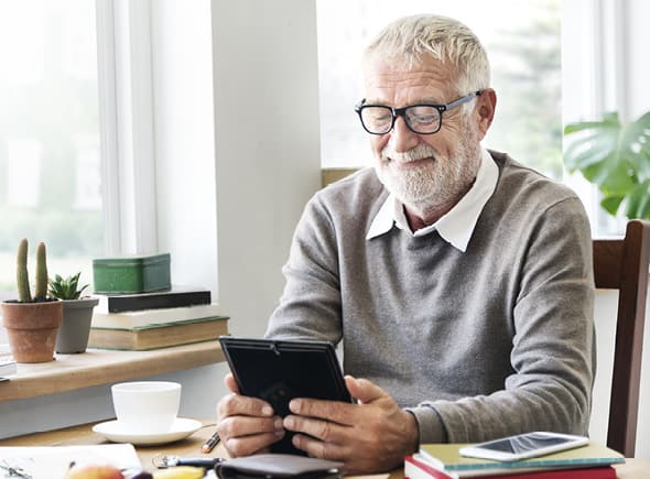 Man smiling and looking at a tablet.