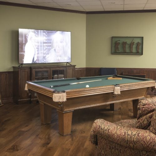 A billiards table in a large room with a couch and TV in Humble, Texas