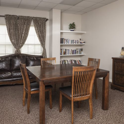 Community room includes a couch, table for four people, and shelves filled with books