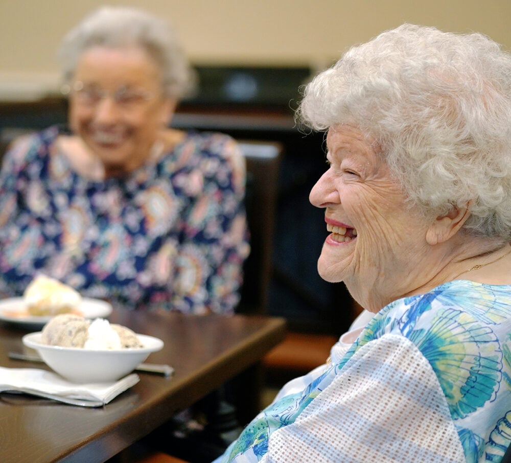 Older adult woman smiles while enjoying ice cream at a senior living community