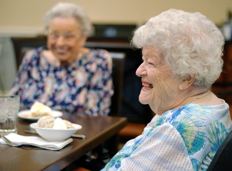 Older adult woman smiles while enjoying ice cream at a senior living community