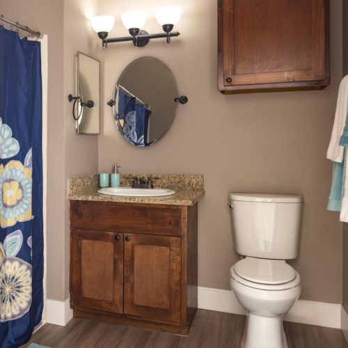 Apartment bathroom includes a sink, toilet, storage and a shower