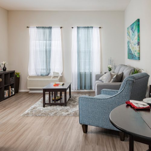 Apartment living room and kitchen includes a couch, chair, TV and small dining area