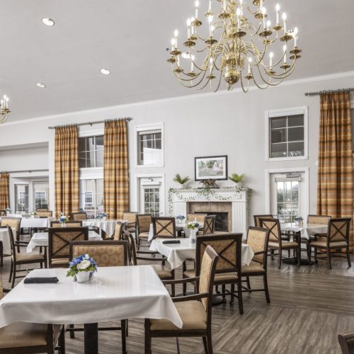 A large and elegant dining room with plenty of seating, a fireplace, large windows and chandeliers in San Antonio, Texas