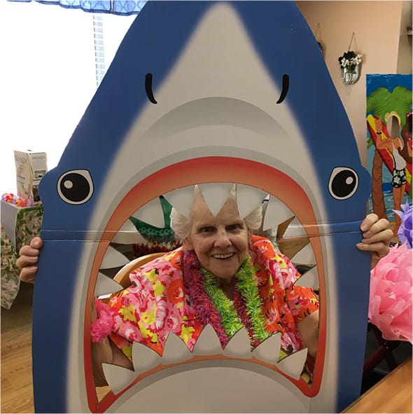 A senior woman posing with her head through a shark cut out in North Richland Hills, Texas.