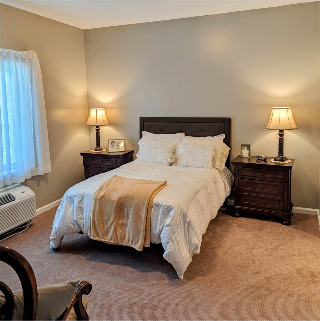 senior living apartment bedroom with a bed, two dressers and a window at Autumn Glen in Greencastle, IN