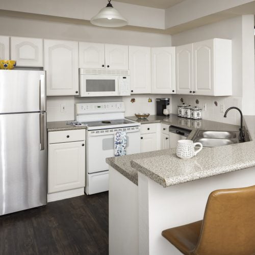 Kitchen with an oven, sink, fridge and microwave at a senior living community in Conroe, Texas