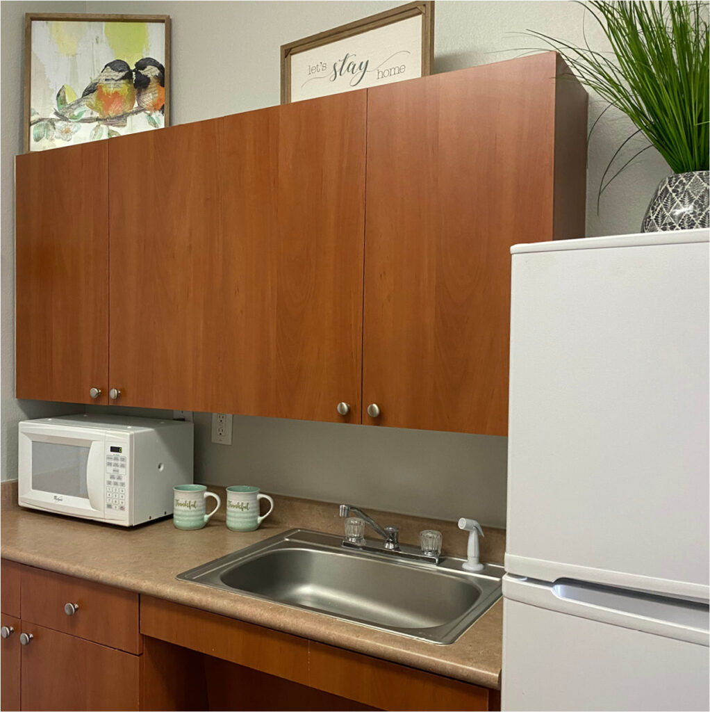 Kitchen in a senior living apartment with a fridge, sink, microwave and cabinets in Lake Granbury, Texas.