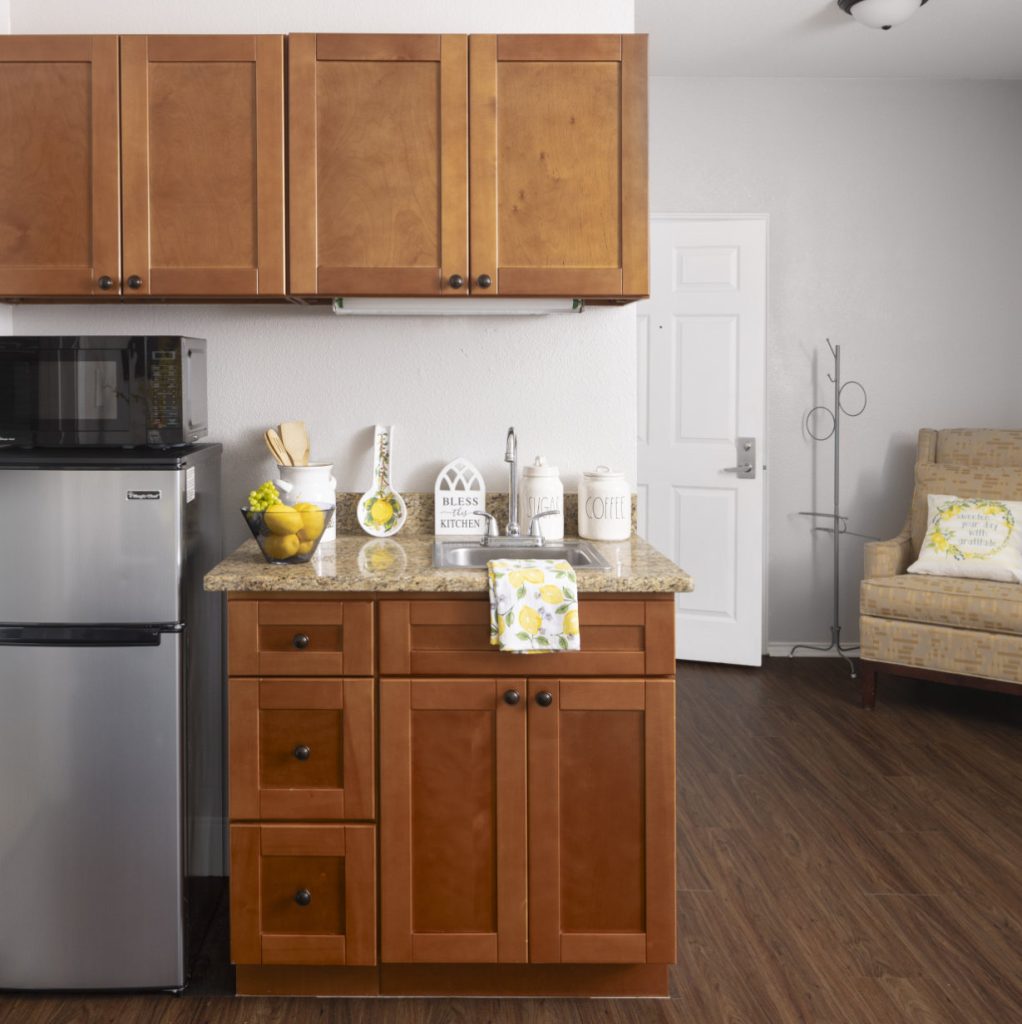 Apartment kitchen includes a sink, fridge, microwave and storage