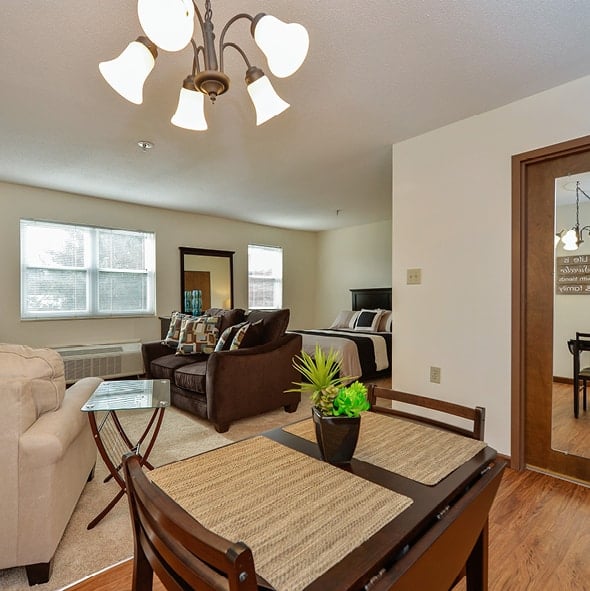 Studio apartment with lounge area, dining area, large bed and a mirror on the bathroom door in Indianapolis, Indiana.