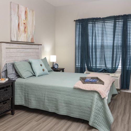 Senior living apartment bedroom with a bed, side tables and a window