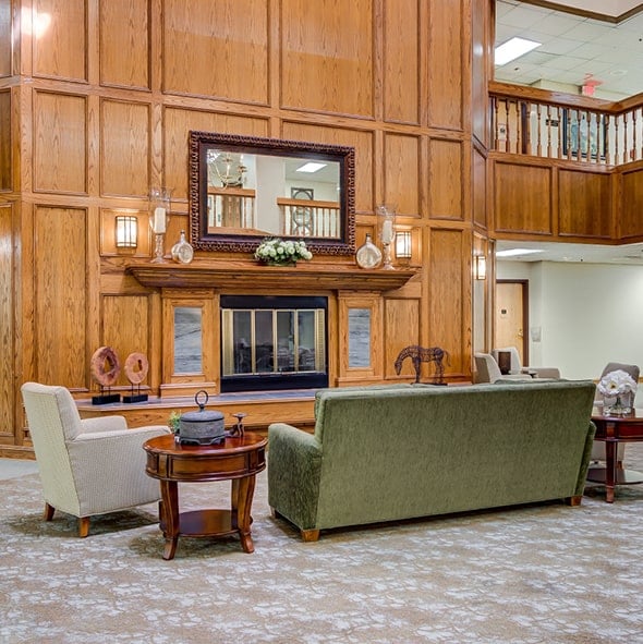 A grand fireplace with wood panel and wainscoting surround and comfortable lounge furniture in Hot Springs, Arkansas..