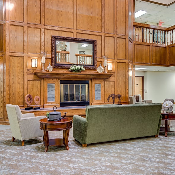 A grand fireplace with wood panel and wainscoting surround and comfortable lounge furniture in Hot Springs, Arkansas..