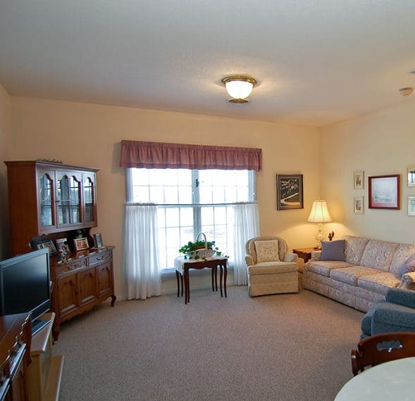 Spacious living room with crown molding, a large window and a doorway opening to a bedroom in Rochester, Indiana..