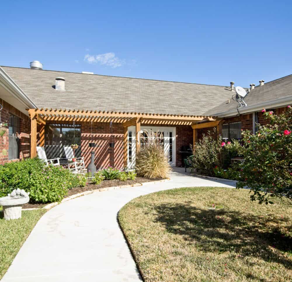 Outside courtyard with seating and walking path at a senior living community in College Station, Texas.