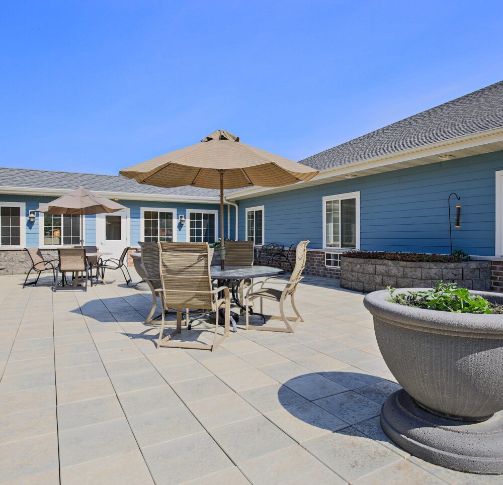 Outdoor patio with tables, chairs and umbrellas at a senior living community in Wisconsin Rapids, Wisconsin.