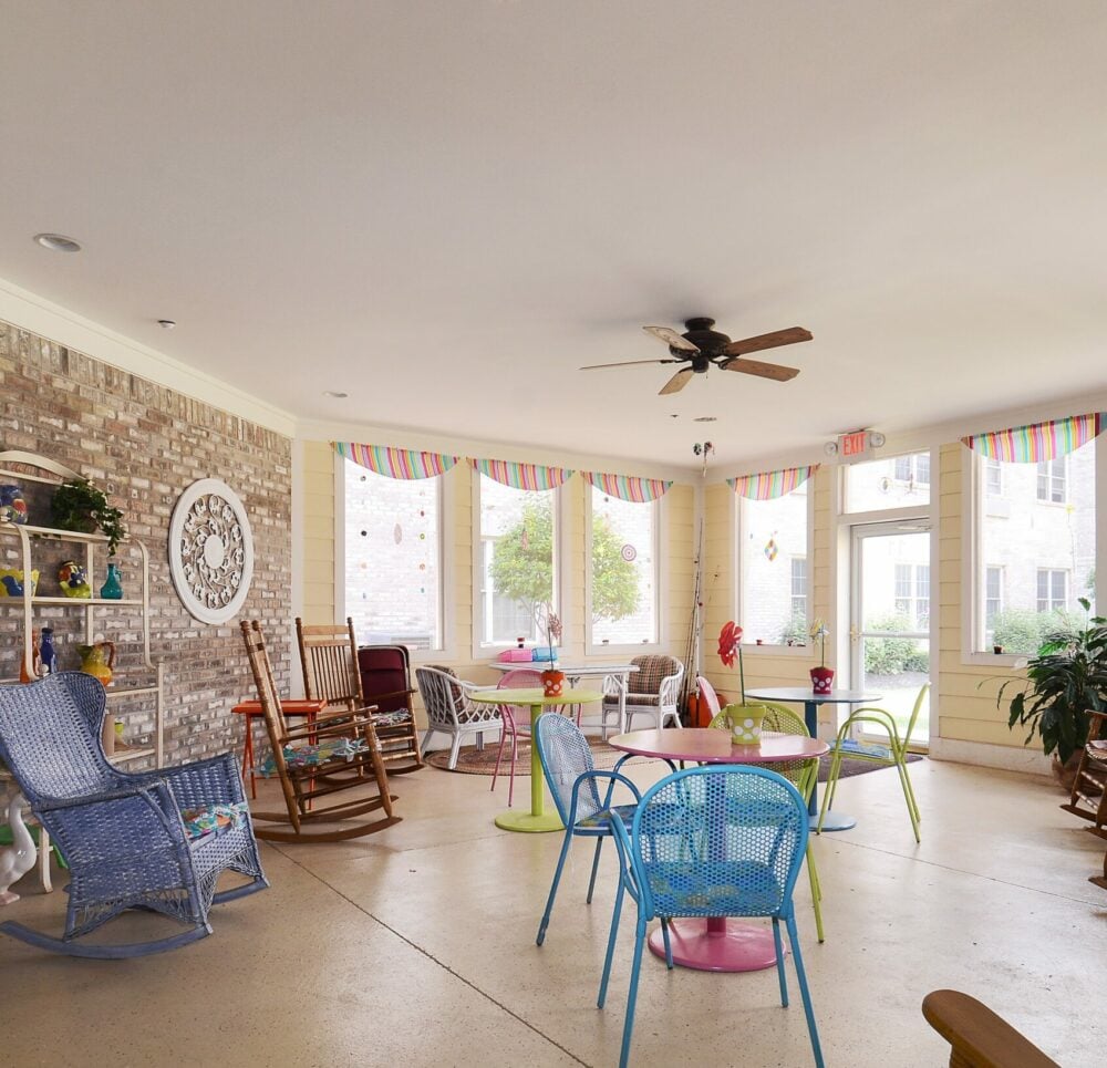 Patio area with rocking chairs, activity tables and lots of natural light at a senior living community in Indianapolis, Indiana.