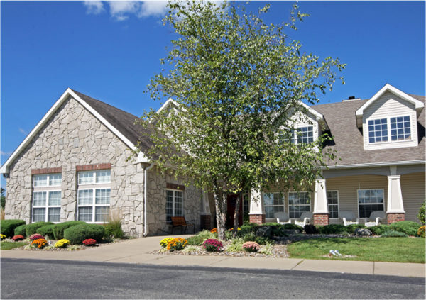 Assisted living community with stone exterior, flowers and white wicker chairs in Jeffersonville, Indiana.