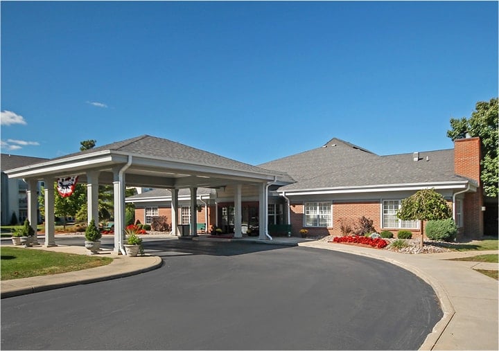 Front entrance of a senior living facility in Williamsville, New York with covered circular drive and lush landscaping.