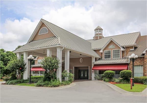 Front entrance of a coastal senior living facility in Pensacola, Florida with a covered driveway.