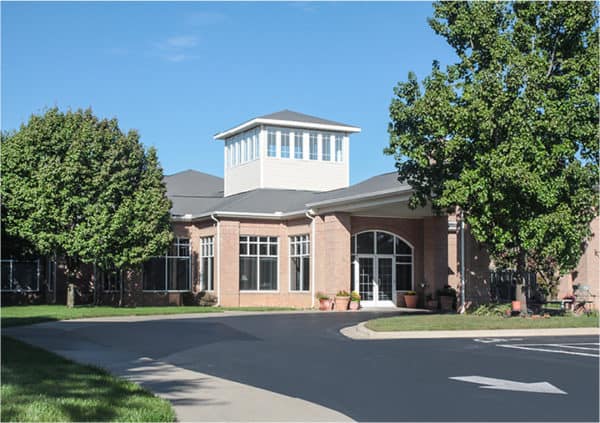 The exterior of a senior living community with a portico entrance, bench seating and landscaping in Springfield, Missouri.