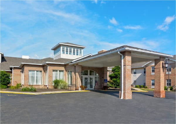 Front entrance of a senior living facility with portico entrance, bench seating and landscaping in Mansfield, Ohio.