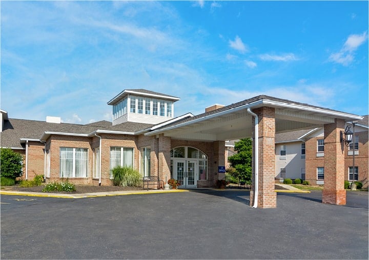 Front entrance of a senior living facility with portico entrance, bench seating and landscaping in Mansfield, Ohio.