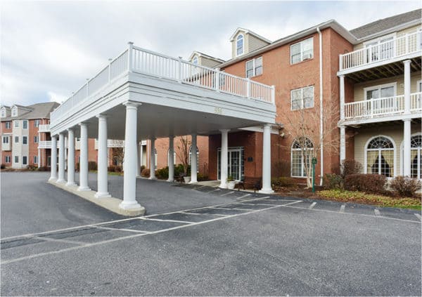 Front entrance of a senior living facility in Springfield, Massachusetts with covered driveway and white columns..