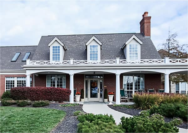 Front entrance of a senior living facility in Hamilton, Ohio with lush landscaping and sidewalk.