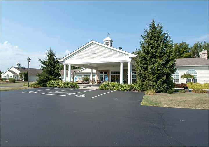 Front entrance of a senior living facility in Columbiana, Ohio with lush landscaping and covered entrance.