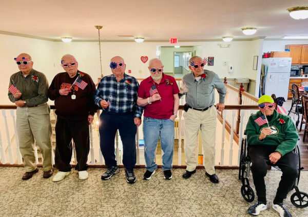 Six older men pose with American-themed décor and flags for Veterans Day in Batesville, Indiana