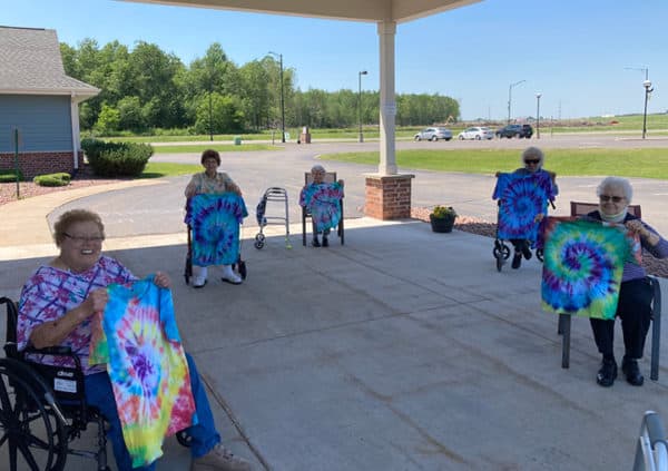 Seniors holding up tie dye t-shirts they made at their senior living community in Colby, Wisconsin.