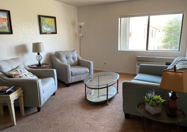 Senior living apartment living room with a couch, two chairs, a table, lamps and a window in Cottonwood, Arizona